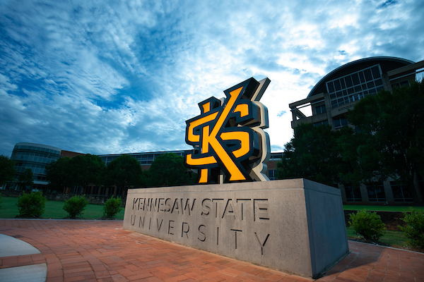 KSU logo statue in front of Kennesaw Hall with blue sky in background